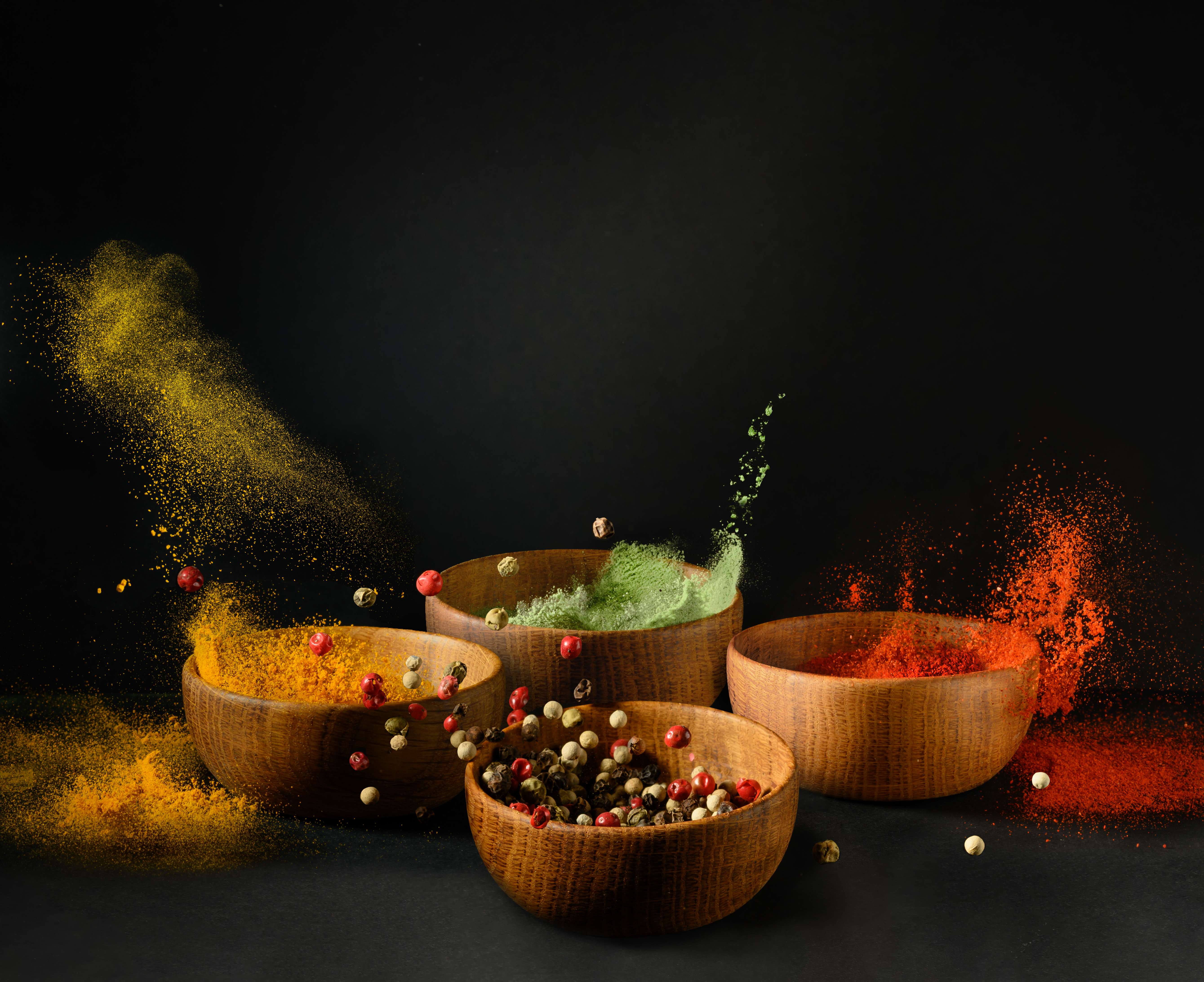 Spices and seasonings powder splash, explosion. Set of colorful spices in wooden bowls, isolated on black background. Freeze motion photo